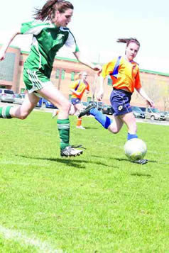 Two soccer players running after the ball.